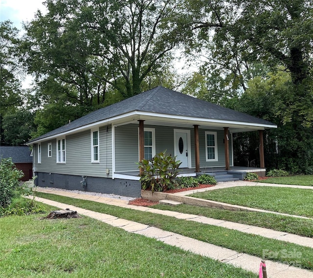 view of front of house with a porch, roof with shingles, and a front yard