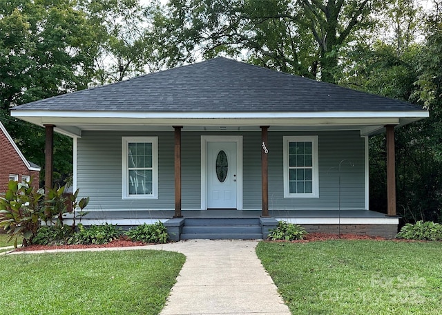 bungalow-style house with covered porch, a shingled roof, and a front yard