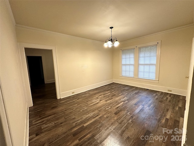 empty room with dark wood-type flooring, a notable chandelier, ornamental molding, and baseboards