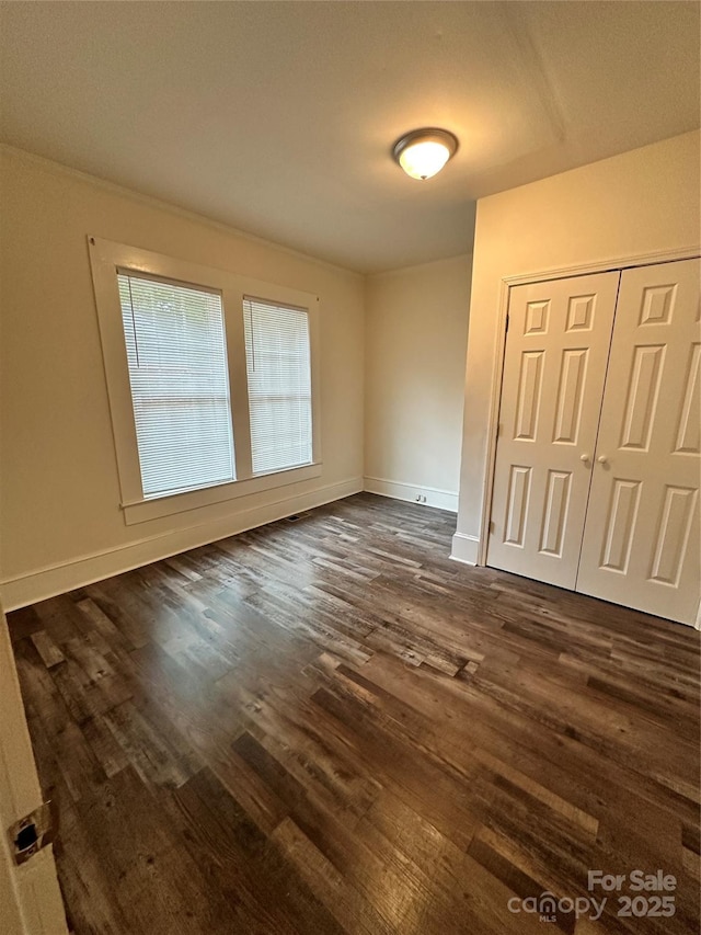 empty room with baseboards and dark wood finished floors