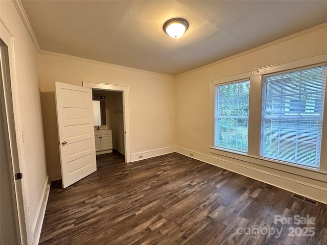 unfurnished bedroom featuring dark wood-style floors, baseboards, visible vents, and crown molding