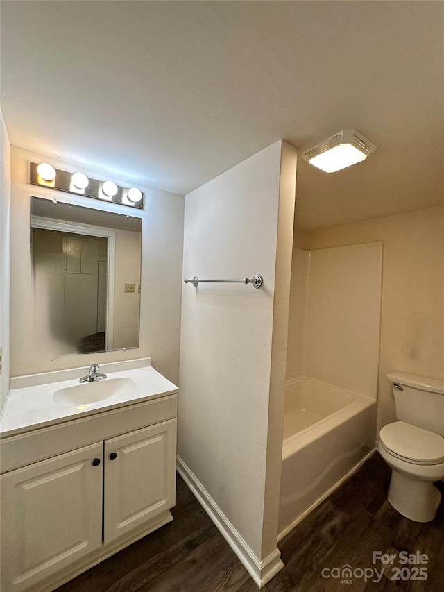 bathroom with toilet, baseboards, wood finished floors, and vanity