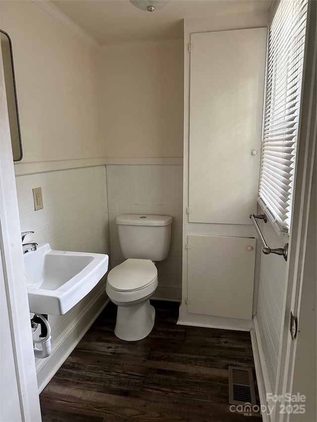 bathroom with visible vents, wainscoting, toilet, wood finished floors, and a sink