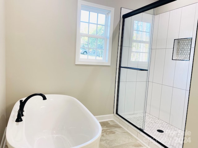 bathroom with a stall shower, a freestanding tub, and baseboards