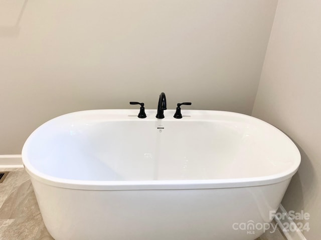 bathroom featuring a soaking tub and baseboards