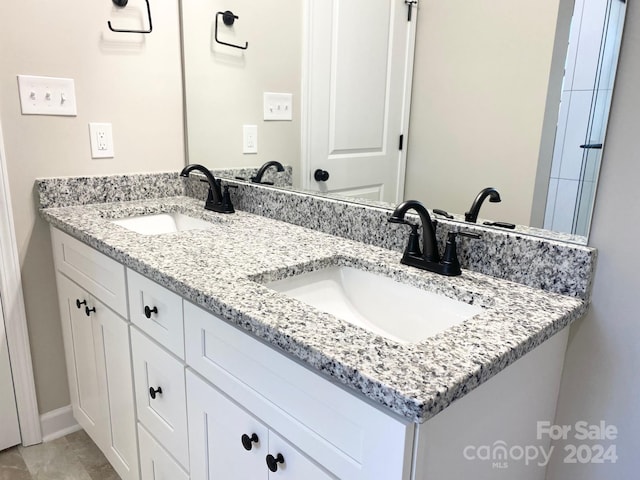 bathroom featuring double vanity, baseboards, and a sink