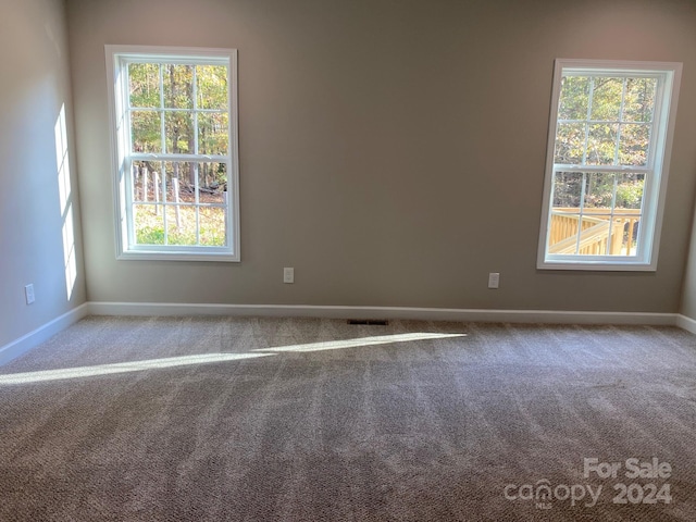 carpeted empty room with visible vents and baseboards