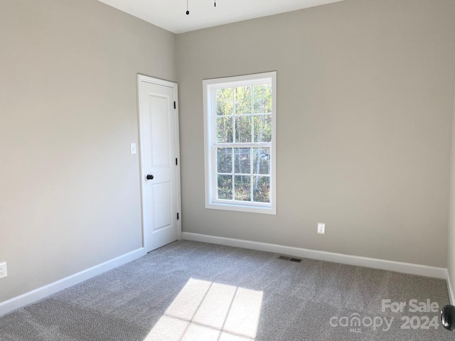 carpeted spare room featuring baseboards and visible vents