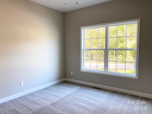 unfurnished room featuring carpet floors, visible vents, and baseboards