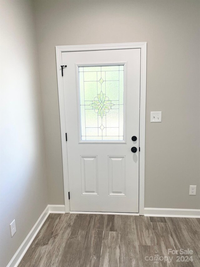 doorway with baseboards and wood finished floors