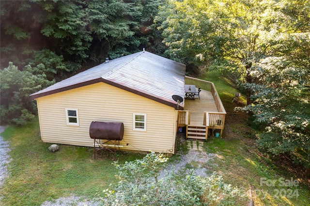 view of property exterior featuring a lawn, a deck, and heating fuel