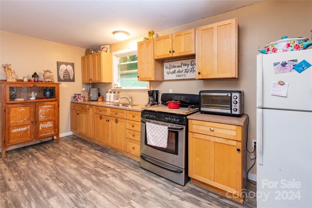 kitchen with light brown cabinetry, light wood-type flooring, white refrigerator, gas range, and sink