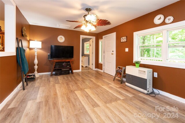 living room featuring light hardwood / wood-style flooring, heating unit, and ceiling fan