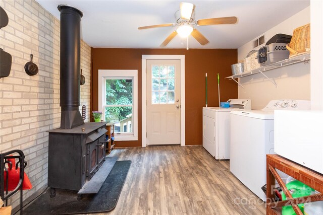 washroom featuring wood-type flooring, plenty of natural light, ceiling fan, and a wood stove