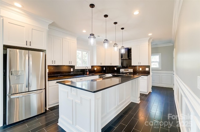 kitchen with white cabinetry, stainless steel appliances, wall chimney range hood, pendant lighting, and a kitchen island