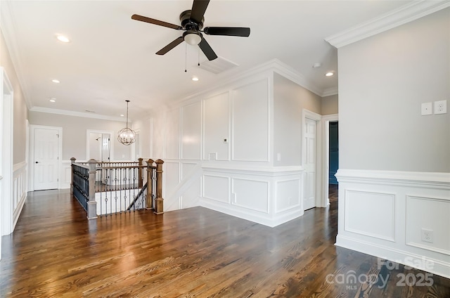 empty room featuring dark wood-type flooring, ceiling fan with notable chandelier, and ornamental molding