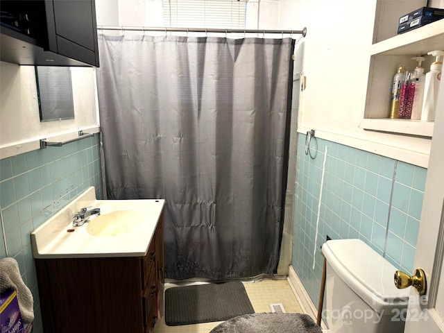 bathroom featuring tile patterned floors, toilet, tile walls, vanity, and curtained shower