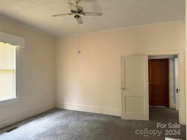 unfurnished room with crown molding, ceiling fan, and dark colored carpet