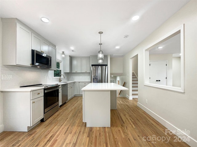 kitchen featuring sink, stainless steel appliances, a center island, and light hardwood / wood-style floors