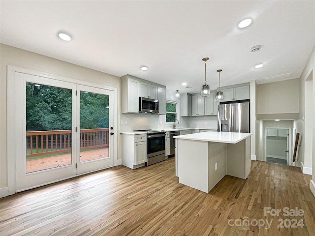 kitchen with stainless steel appliances, a kitchen island, and light hardwood / wood-style floors