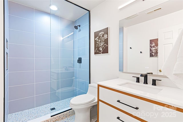 bathroom featuring vanity, toilet, and a tile shower