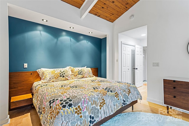 bedroom featuring vaulted ceiling with beams, wooden ceiling, light wood-type flooring, and a closet