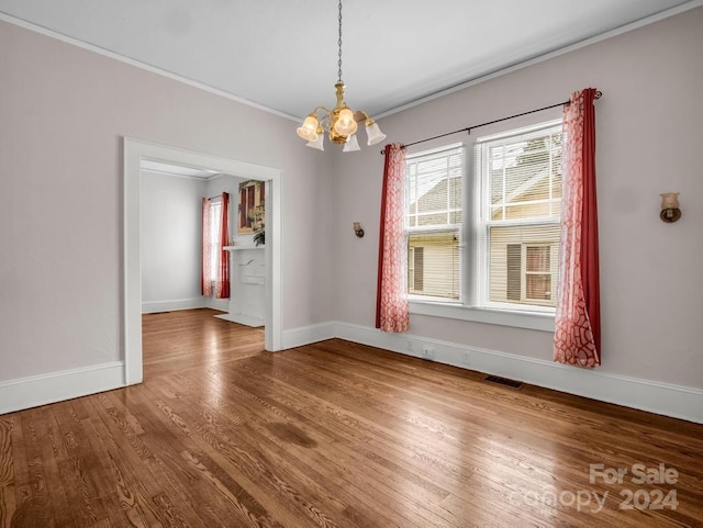 unfurnished dining area with a notable chandelier, crown molding, and wood-type flooring