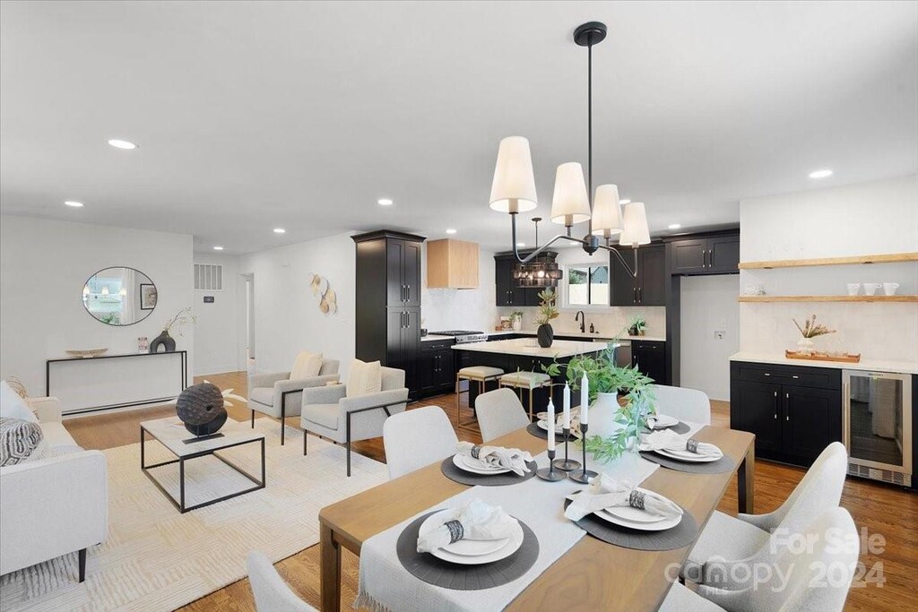 dining room with wine cooler, an inviting chandelier, and light hardwood / wood-style floors