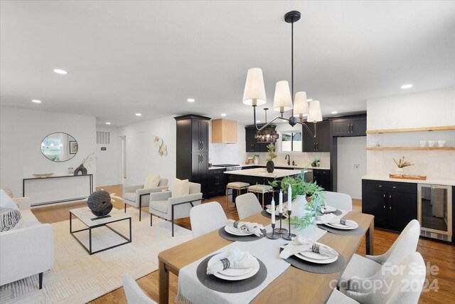 dining room with wine cooler, an inviting chandelier, and light hardwood / wood-style floors