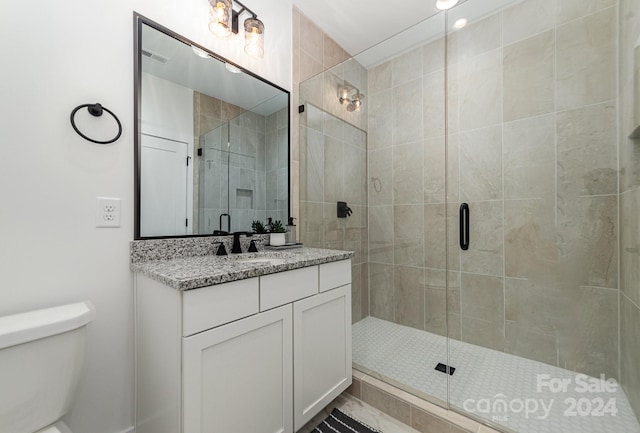 bathroom featuring an enclosed shower, toilet, and vanity