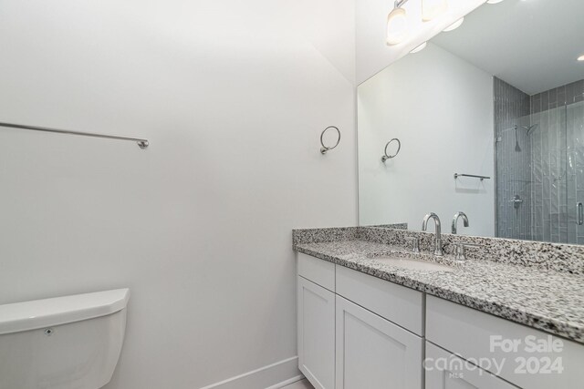 bathroom featuring toilet, a tile shower, and vanity