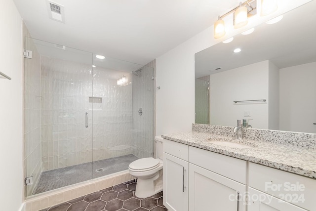 bathroom featuring tile patterned flooring, toilet, vanity, and a shower with shower door