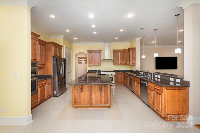 kitchen featuring appliances with stainless steel finishes, a kitchen island with sink, crown molding, wall chimney range hood, and pendant lighting