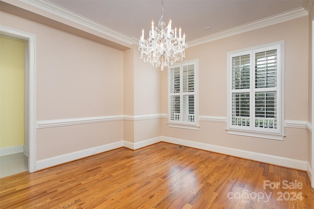 empty room featuring light wood-type flooring, ornamental molding, and a chandelier