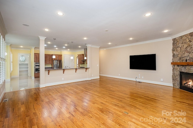 unfurnished living room with a fireplace, ornamental molding, and light wood-type flooring