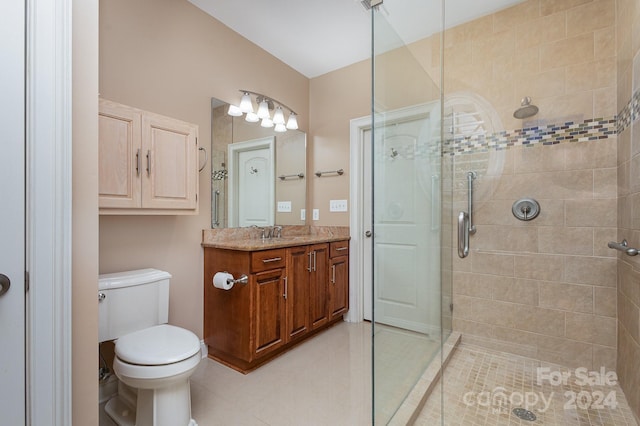 bathroom featuring tile patterned floors, vanity, a shower with shower door, and toilet