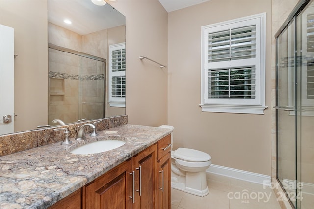 bathroom featuring tile patterned floors, vanity, toilet, and a shower with shower door