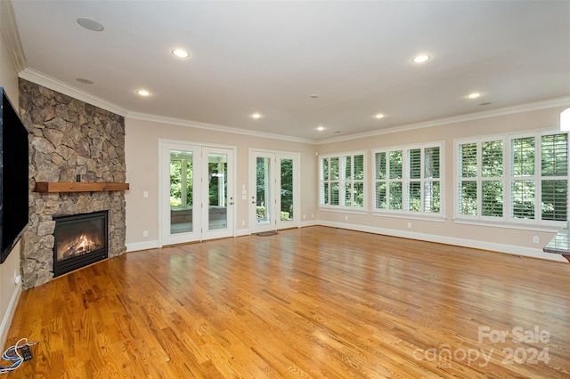 unfurnished living room featuring crown molding, a fireplace, plenty of natural light, and light hardwood / wood-style flooring