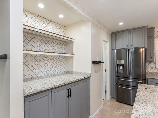 kitchen with stainless steel fridge with ice dispenser, backsplash, light tile patterned floors, and light stone countertops