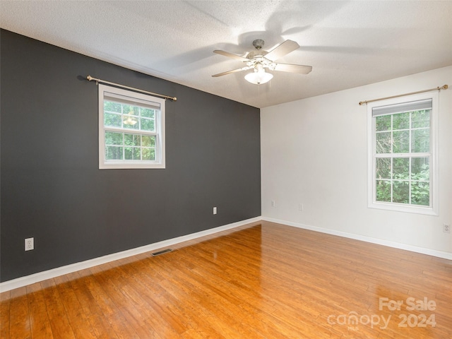 unfurnished room with ceiling fan, light hardwood / wood-style flooring, and a textured ceiling