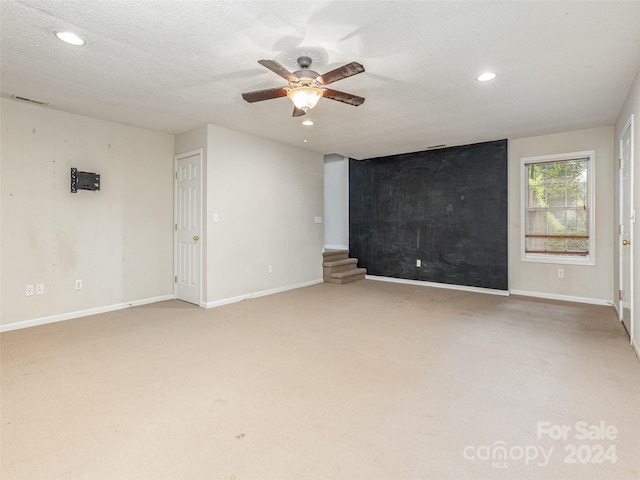 empty room with a textured ceiling, carpet flooring, and ceiling fan