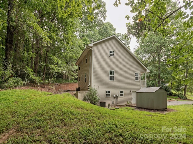 view of property exterior with central AC, a storage shed, and a lawn