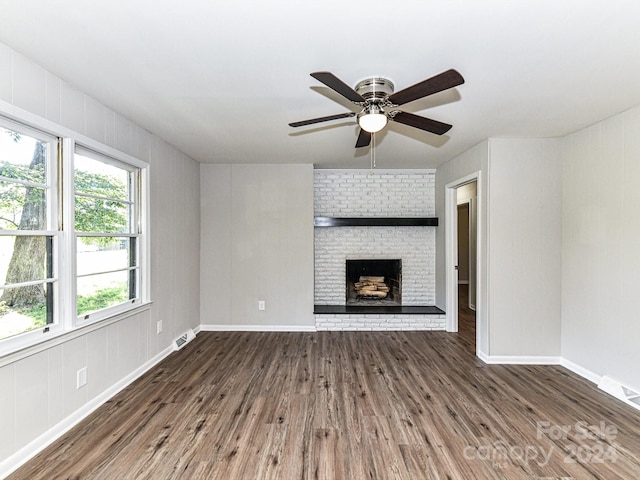 unfurnished living room featuring brick wall, a fireplace, dark hardwood / wood-style flooring, and ceiling fan