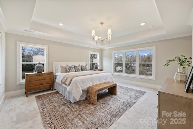 bedroom with light carpet, a chandelier, a tray ceiling, and multiple windows