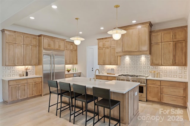 kitchen with hanging light fixtures, light hardwood / wood-style floors, high end appliances, and a center island with sink