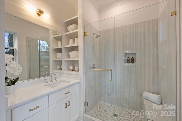 bathroom featuring a shower with shower door and vanity