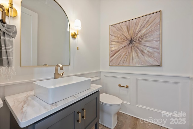 bathroom with toilet, hardwood / wood-style flooring, and vanity