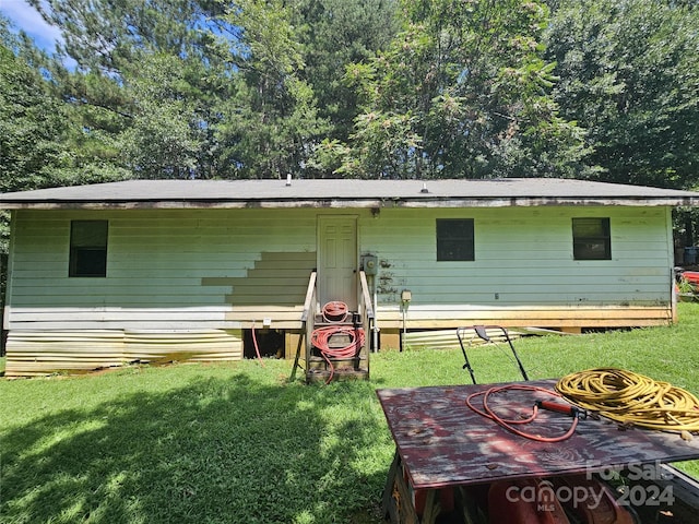 rear view of property featuring a lawn