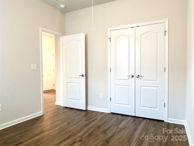 unfurnished bedroom featuring dark hardwood / wood-style flooring and a closet