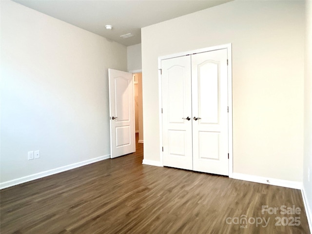 unfurnished bedroom with a closet and dark wood-type flooring